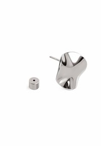 Silvermetallföremål med en böjd form och slät yta bredvid en cylindrisk del. Båda har en polerad yta.