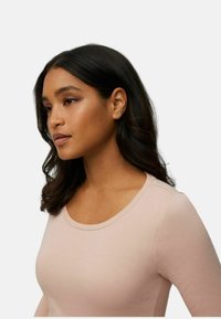 Camiseta de manga larga rosa claro con escote redondeado y textura suave, que presenta sutiles detalles de costura a lo largo de los hombros.