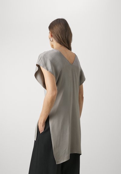 Gray, short-sleeve top with a V-neck and side slits, made from smooth fabric. Back features a subtle cut-out design.
