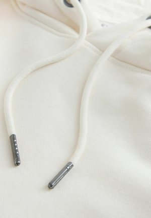 Cremefarbener Hoodie mit weicher Textur, rundem Ausschnitt und verstellbaren Kordelzügen mit Metallenden, der ein einfaches und klares Design zeigt.