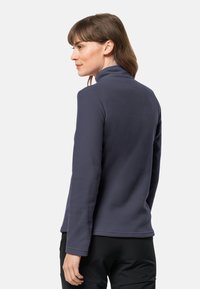 Marineblauwe fleece trui met een hoge kraag, lange mouwen en een gladde textuur. Kenmerkt zich door een rechte onderkant en minimale details.