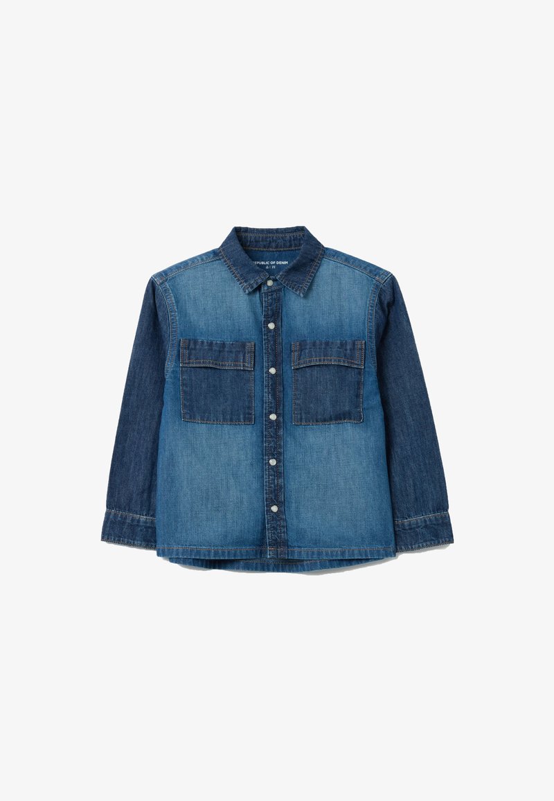 Camicia di denim con due tasche frontali, chiusura a bottoni e tonalità di blu a contrasto. Maniche lunghe con polsini abbottonati. Tessuto leggero.
