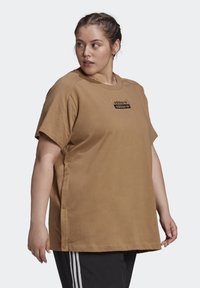 Bruine katoenen t-shirt met korte mouwen, ronde hals, zijknopen en een zwart logo op de voorkant. Soepele textuur en een ontspannen pasvorm.