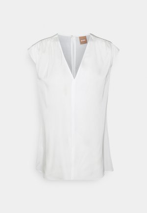 Blouse blanche sans manches avec col en V, légers fronces aux épaules et petite fermeture à bouton dans le dos avec étiquette BOSS visible.