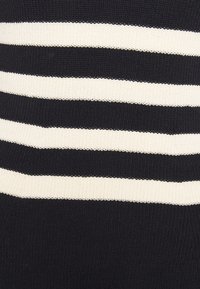 Strickstoffoberteil mit horizontalen schwarzen und cremfarbenen Streifen. Die Textur ist gerippt, mit einem glatten Finish an den Kanten.