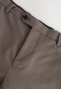 Pantaloni personalizați de culoare maronie, cu o textură netedă, având un sistem de închidere frontal cu nasturi și bucle pentru curea. Cusăturile sunt finisate cu atenție pe margini.