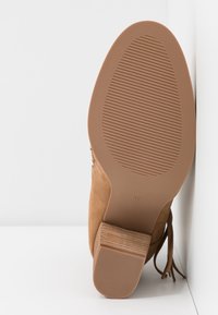 Bottine en daim marron avec une semelle en caoutchouc texturée à rainures horizontales et un talon empilé, taille indiquée 37 sous la semelle.