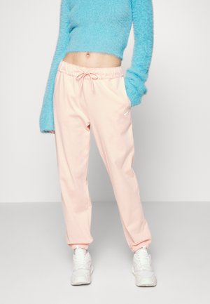 Pantalones jogger rosa claro con cintura elástica y tobillos acampanados, combinados con un suéter corto azul de felpa y zapatillas blancas.