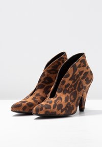 Leopardenmuster hohe Stiefeletten mit spitzem Zeh, aus weichem Wildleder, mit ausgeschnittenen Seiten und einem strukturierten braun-schwarzen Muster.