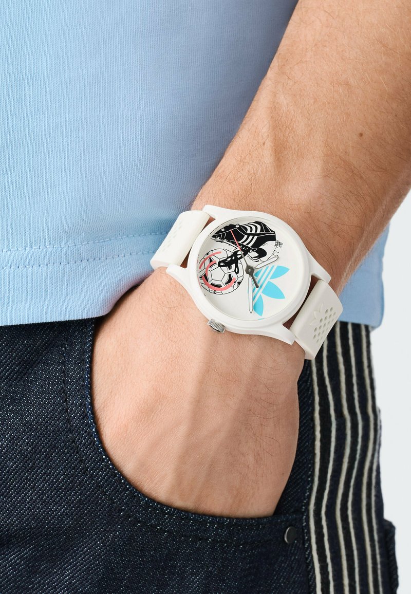 Witte polshorloge met een ronde wijzerplaat, met een kleurrijk grafisch ontwerp met een schedel, een voetbal en blauwe accenten. Siliconen band.