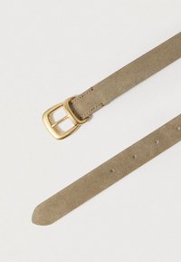 Beežist seemisnahast vöö ruudukujulise kuldse metallist pandlaga, mis sisaldab mitut reguleerimisaasa kogu pikkuses ja on siledapinnaline.