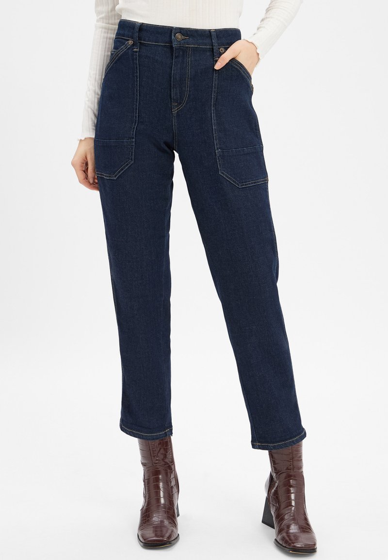 Dark blue denim pants with a high waist, straight-leg cut, two front pockets, and visible stitching. Worn with brown textured ankle boots.