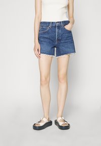 Farkkuhousut, joissa on repaleinen helma, vaaleansininen väri ja klassinen viiden taskun muotoilu. Yhdistetty beigen värisiin platform-sandaaleihin, joissa on solki.