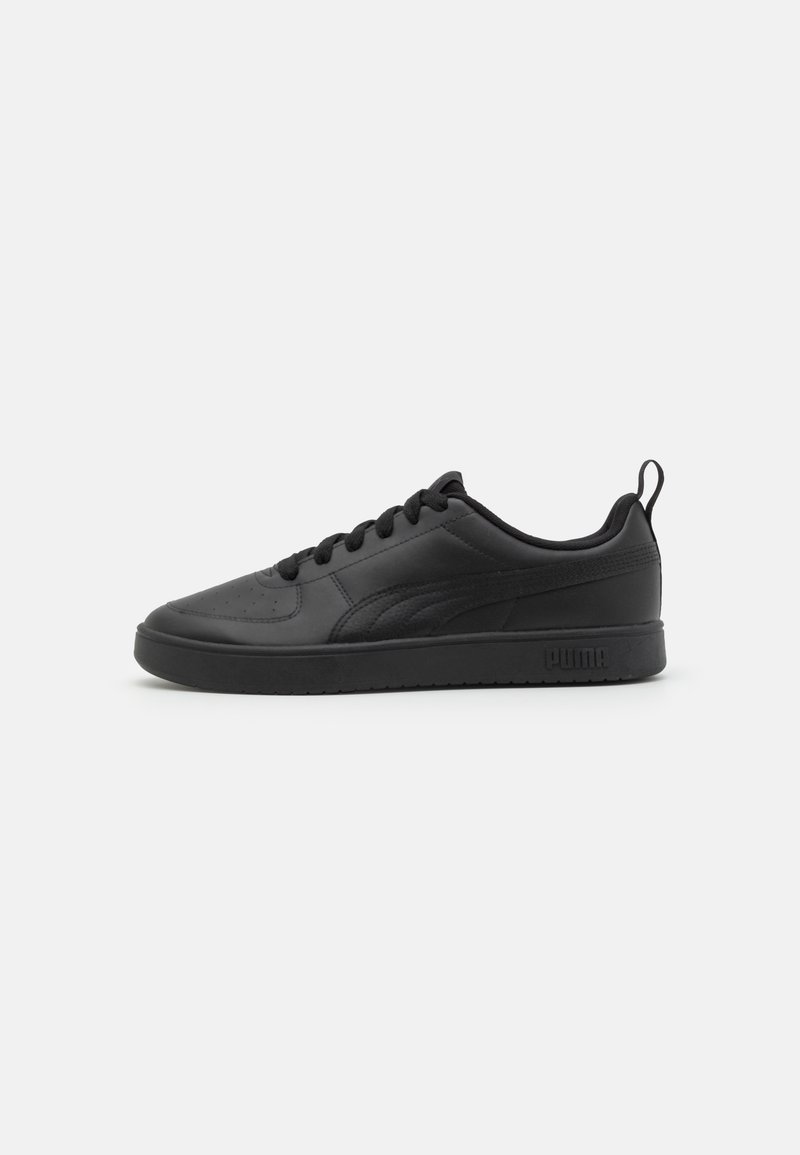 Chaussures de sport noires en matériau synthétique lisse, dotées d'une coupe basse, de lacets plats et d'une semelle texturée avec un logo sur le côté.