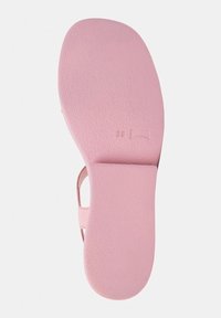 Rosa sandalsole med strukturerad yta, med storleksmarkör "38" inristad i materialet. Överlag slät, med öppna remmar på sidan.