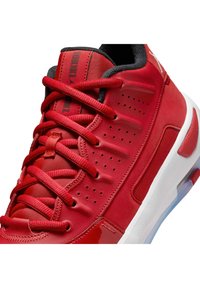 Rode synthetische sneaker met een gestructureerde bovenkant, gewatteerde kraag, ronde veters, geperforeerde details en een witte en doorzichtige rubberen zool.