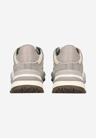 Sneaker grigie e beige caratterizzate da una combinazione di camoscio e pelle, con una suola testurizzata e un marchio sul tallone. Punta arrotondata e colletto imbottito.