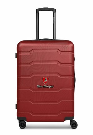 Maleta rígida roja con cuatro ruedas y asa telescópica, con el logo de Tonino Lamborghini en el centro frontal.
