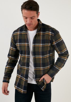 Cămașă din flanel cu un model în carouri verzi, bleumarin și galbene, mâneci lungi, deschidere cu nasturi și o croială lejeră. Țesătură din amestec de bumbac.