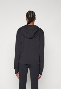 Black hoodie with a spacious hood, ribbed cuffs, and hem; made from soft, textured fabric; viewed from the back with a smooth finish.