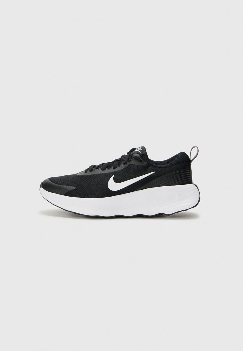Botte de sport noire avec une tige en maille texturée, semelle plate blanche et un logo swoosh blanc bien en vue. Elle dispose de lacets et d'une languette.