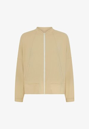 Beige színű zipzáras dzseki, kerek nyakkal, hosszú ujjakkal, két elülső zsebbel és sima anyagtextúrával. Raglán ujjak szépen kidolgozva.