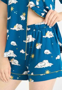 Turkos pyjamas-set med vita kaniner och moln, i kombination med gula stjärndetaljer. Lättviktig tyg; toppen har knappar och shortsen har elastisk midja.