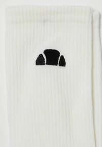 Calcetín blanco de canalé con un logotipo bordado en negro que muestra semicírculos en la parte superior. Textura suave, diseñado para comodidad y ajuste.