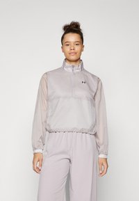Light gray pullover jacket with a mock neck, zip closure, and elastic hem. Made from a smooth, lightweight material with logo accent.