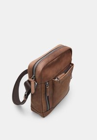 Borsa a tracolla in pelle marrone con due scomparti con zip, una tasca frontale e una tracolla regolabile marrone. Texture liscia e dettagli cuciti.