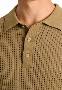 Strick-Polohemd in Khaki mit strukturierten Löchern, ausgestattet mit einem Kragen, einer Drei-Knopf-Leiste und einem strukturierten Stoff.