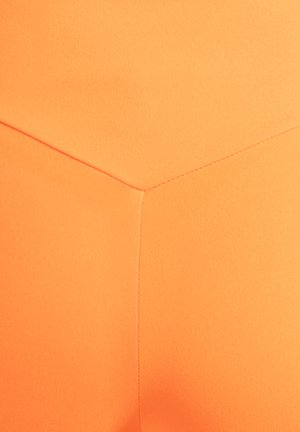 Pomarańczowa tkanina sportowa o gładkiej fakturze z wzorem szew w kształcie jodełki. Brak widocznych elementów metalowych lub wzorów.