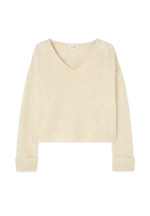 Pull cropped couleur crème avec un col en V, des manches longues et des poignets côtelés. Fabriqué en tissu doux et texturé. Design simple sans motifs.