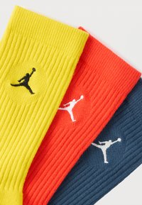 Kolm paari soonikkoes sokke: kollased musta logoga, punased valge logoga, tumesinised valge logoga. Igal paaril on ümmarguse kujundusega logo.