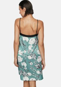 Floral satijnen slipjurk in teal met zwarte accenten. Kenmerken zijn verstelbare dunne bandjes en een aansluitende silhouet met een lichte, gladde textuur.