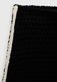 Svart virkadt textil med en texturerad yta och en krämfärgad virkads kant längs en kant. Mjukt och hållbart material.