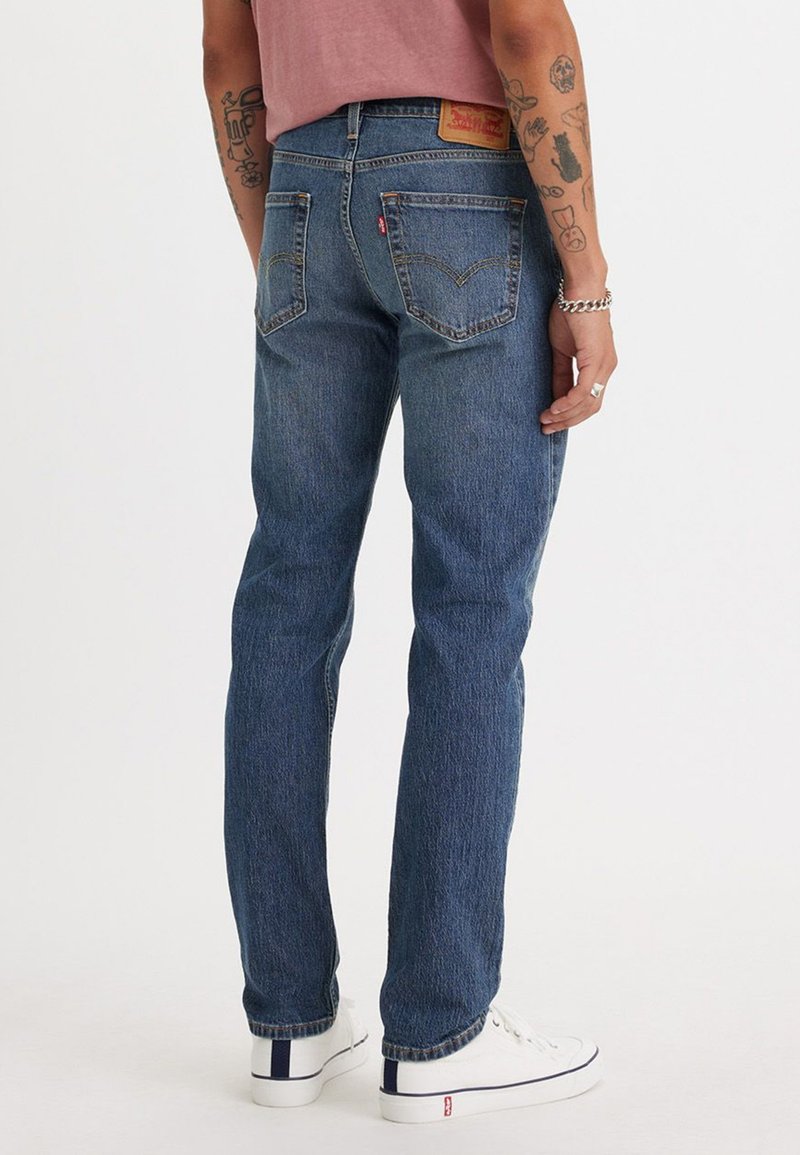 Jeans in denim blu con taglio dritto, design a cinque tasche, sbiadimento sottile e un patch in pelle del marchio sulla cintura posteriore.