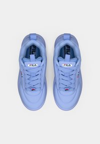 Ζευγάρι ανοιχτόμπλε αθλητικά παπούτσια FILA με χονδρές κορδόνια, λογότυπα της μάρκας στη γλώσσα, στις πλευρές και στη σόλα, απεικονισμένα από πάνω σε λευκό φόντο.