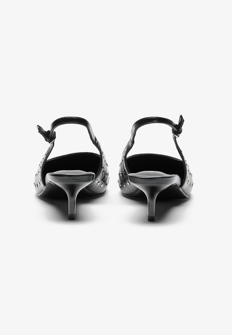 Sandales à talons noirs avec une bride au niveau de la cheville, ornées de clous métalliques, présentant un bout arrondi et un talon aiguille étroit.