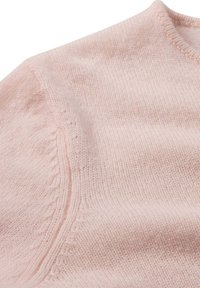 Sanfter, rosa gestrickter Pulloverstoff, der die Schulternähte und Details des gerippten Kragens zeigt.