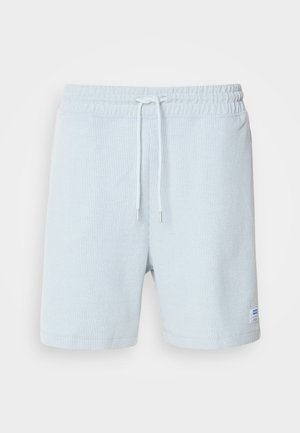 Hellblaue gerippte Shorts mit einem elastischen Bund, Kordelzugdetails und einem kleinen Etikett auf der linken Seite. Aus weichem Baumwollmaterial.