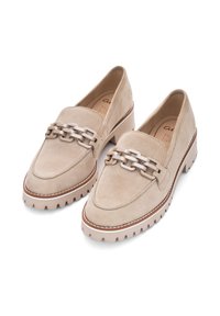 Beige suede loafers with a thick, beige rubber sole, featuring a decorative chain link accent across the strap and stitched detailing.