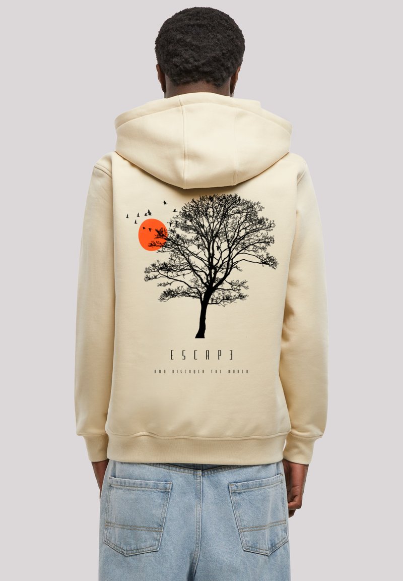 Beige hoodie met een zwarte silhouet van een boom, een oranje zon en vogels in vlucht. Tekst luidt "ONTKLOOIEN EN DE WERELD ONTDEKKEN."