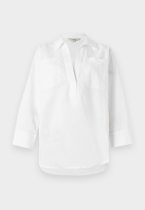 Cămașă albă din in, cu guler, mâneci trei sferturi și două buzunare la piept. Textură netedă și croială lejeră cu tiv despicat.