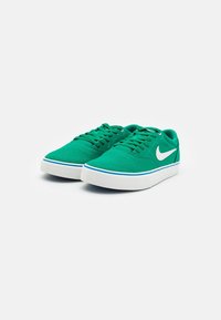 Green canvas sneakers with white accents, featuring a round toe, flat lace-up design, and a thick white rubber sole with blue trim.