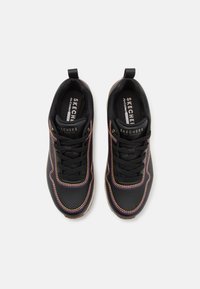 Pár černých tenisek Skechers s multicolor švy, černými tkaničkami a poutky, zobrazený z horního pohledu na bílém pozadí.