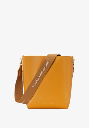 Sac à main en cuir jaune en forme de seau avec une texture lisse, doté d'une bandoulière réglable marron étiquetée "VICTORIA HYDE LONDON" et d'accents en métal doré.