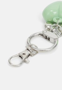 Accessoire porte-clés en plastique vert avec un clip en métal argenté et un anneau porte-clés, à la texture lisse et à la forme arrondie.