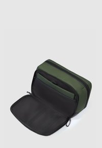 Bolsa rectangular con cremallera en nylon verde oscuro con una superficie texturizada. Presenta un interior negro con compartimentos elásticos y bolsillos.