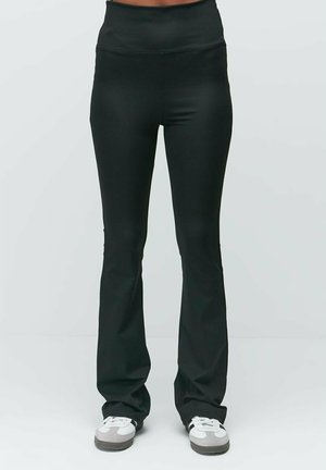 Black flared leggings with a high waist, made of smooth material, featuring a fitted design that tapers down to the ankle.